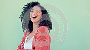 Freedom, happy and smile with a woman laughing and standing arms crossed outside on a green wall background. Funny, joke