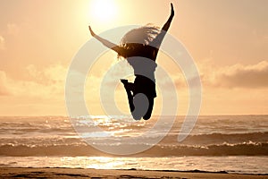 Freedom, jump and sunset with woman at beach for travel, celebration and winner. Success, summer and silhouette with