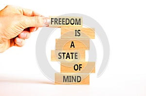 Freedom in mind symbol. Concept words Freedom is a state of mind on wooden block. Beautiful white table white background.