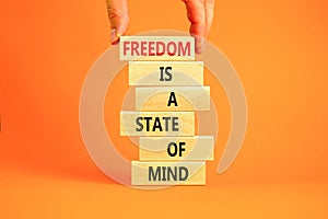 Freedom in mind symbol. Concept words Freedom is a state of mind on wooden blocks on a beautiful orange table orange background.