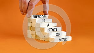 Freedom in mind symbol. Concept words Freedom is a state of mind on wooden blocks on a beautiful orange table orange background.