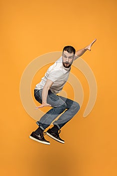 Freedom in moving. handsome young man jumping against orange background