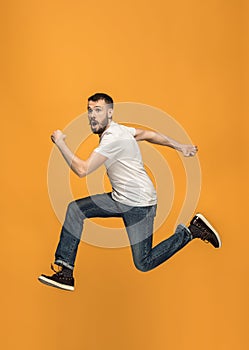 Freedom in moving. handsome young man jumping against orange background