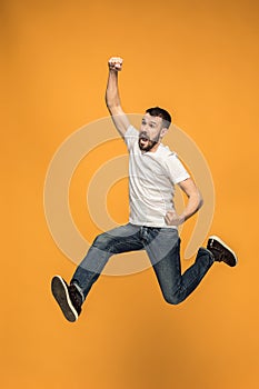 Freedom in moving. handsome young man jumping against orange background