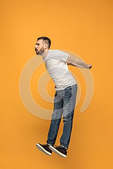 Freedom in moving. handsome young man jumping against orange background