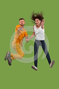 Freedom in moving. Pretty young couple jumping against green background