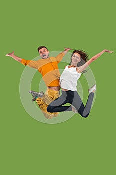 Freedom in moving. Pretty young couple jumping against green background