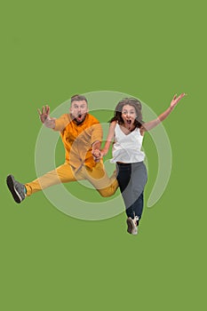 Freedom in moving. Pretty young couple jumping against green background