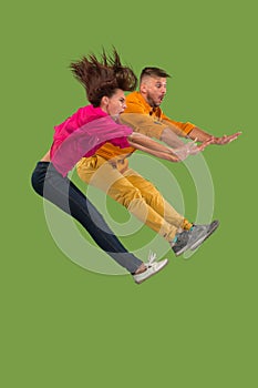 Freedom in moving. Pretty young couple jumping against green background