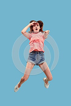 Freedom in moving. Pretty young woman jumping against blue background