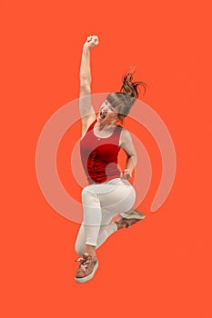 Freedom in moving. Pretty young woman jumping against orange background