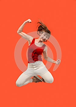 Freedom in moving. Pretty young woman jumping against orange background