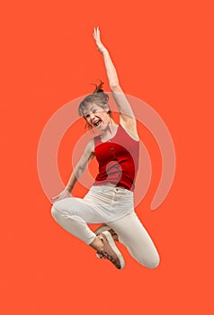 Freedom in moving. Pretty young woman jumping against orange background