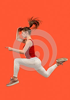 Freedom in moving. Pretty young woman jumping against orange background