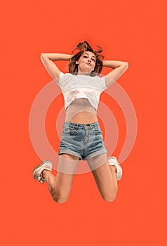Freedom in moving. Pretty young woman jumping against orange background