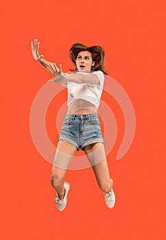 Freedom in moving. Pretty young woman jumping against orange background