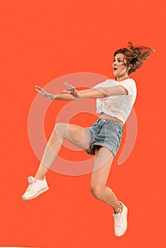 Freedom in moving. Pretty young woman jumping against orange background