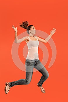 Freedom in moving. Pretty young woman jumping against orange background