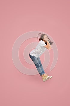 Freedom in moving. Pretty young woman jumping against pink background