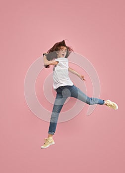 Freedom in moving. Pretty young woman jumping against pink background