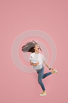 Freedom in moving. Pretty young woman jumping against pink background