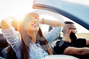 Freedom of the open road.Young Couple Driving Along Country Road In Open Top Car