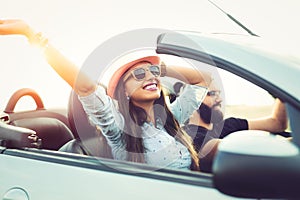 Freedom of the open road.Young Couple Driving Along Country Road In Open Top Car.