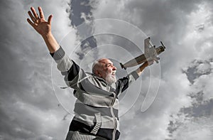 freedom of senior retired man. mature man at retirement. old man on sky background with toy plane