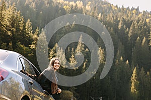 Freedom, travel and a happy woman looking back through the car window. Relaxation and happiness on the road of rural