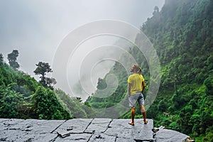 Freedom. Traveler on the edge of a cliff among the jungle and mountains