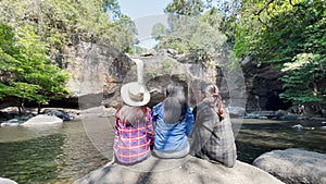 Freedom traveler group of woman sitting waterfall front on stone and embrace enjoying a beautiful nature.