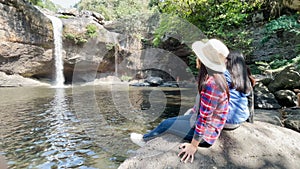 Freedom traveler group of woman sitting waterfall front on stone and embrace enjoying a beautiful nature.