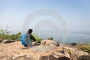 Freedom traveler woman alone sitting on mountain with bag