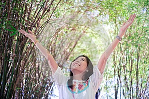 Freedom woman arms raised enjoying the fresh air in green bamboo trees