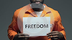 Freedom word on cardboard in hands of Afro-American prisoner, asking for amnesty