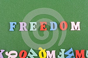 FREEDOM word on green background composed from colorful abc alphabet block wooden letters, copy space for ad text. Learning