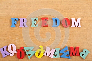 FREEDOM word on wooden background composed from colorful abc alphabet block wooden letters, copy space for ad text. Learning