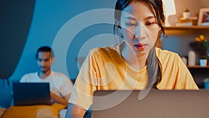 Freelance asia couple man and woman in casual wife focus financial work business in laptop computer on desk at night happy husband