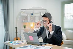 Freelance business man calling on mobile smartphone while working with laptop on table, businessman mobile phone to calling with