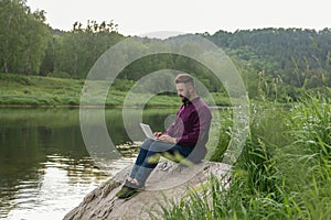 Freelance Concept, Remote Office. Young bearded man, businessman with laptop sits outdoor on summer day