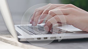 A freelance girl is typing a letter about work on the laptop keyboard. Close-up of a woman's fingers typing on a