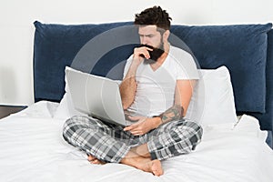 Freelance job. Stay in bed and keep working. Freelance benefits. Man surfing internet or working online. Hipster bearded