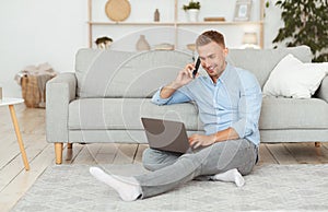 Freelance man sitting on floor using phone and pc