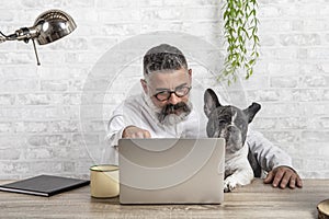 Freelance man working from home with his dog sitting together in office