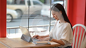 Freelance servant girl is using a laptop to do a new project to present customers in a coffee shop