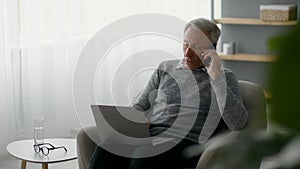 Freelance Work On Retirement. Senior man using cellphone and laptop at home