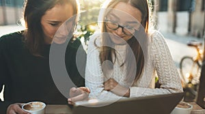 Freelancer communicate on project in cafe outdoor, girls using digital tablet. Friends talking in sun Barcelona. Working business