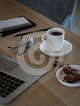 Freelancer desktop with laptop, notes, glasses, coffee cup and cookies