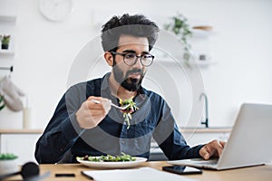 Freelancer dining while typing on computer in home workplace