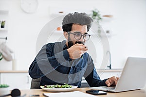 Freelancer dining while typing on computer in home workplace
